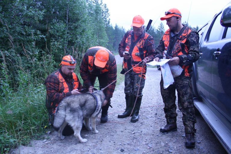 Metsästäjät koiran kanssa valmistautumassa jahtiin.