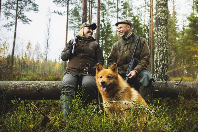 Metsästäjät jahdissa koiran kanssa.